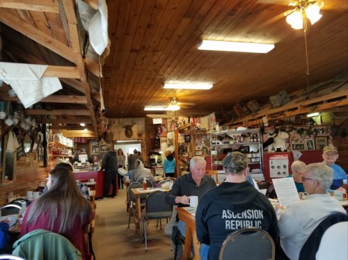 A cozy restaurant interior with wooden decor, patrons dining, and a bustling atmosphere.