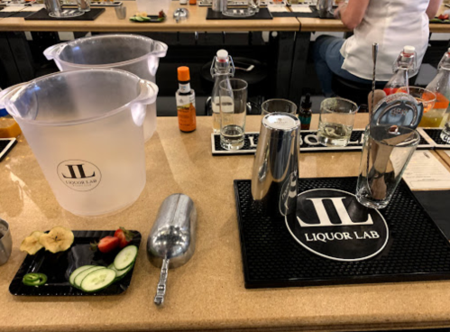A bar setup at Liquor Lab with cocktail ingredients, a shaker, and ice buckets on a countertop.