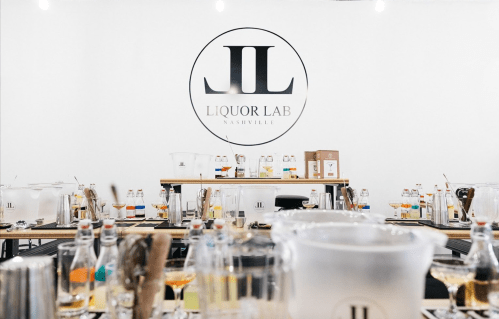 A spacious workshop setting at Liquor Lab in Nashville, featuring tables with various drink-making supplies and equipment.