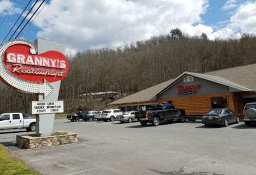 A roadside view of Granny's Restaurant with a vintage sign and parked cars, set against a wooded hillside.