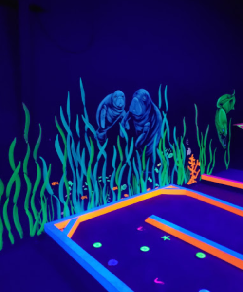 Glow-in-the-dark mural of manatees and sea life in a vibrant underwater scene.
