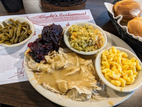 A plate of turkey with gravy, macaroni and cheese, green beans, stuffing, and rolls at Clyde's Restaurant.
