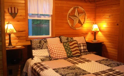 Cozy wooden bedroom with a patchwork quilt, decorative pillows, and lamps, featuring a rustic star on the wall.