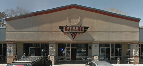 Exterior of a restaurant called "Garage Kitchen & Arcade," featuring a large sign and outdoor seating.