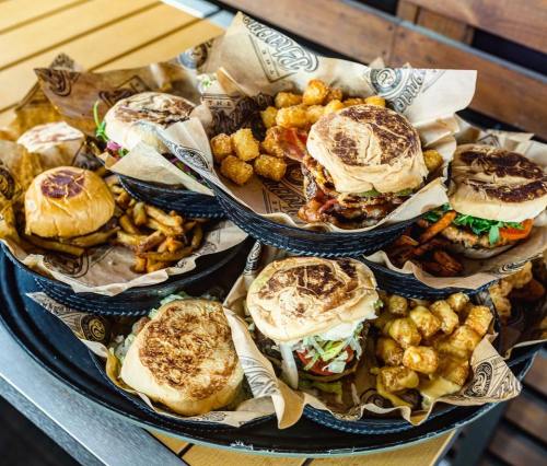 A variety of burgers and tater tots served in baskets on a wooden table.