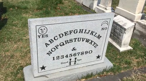 A gray gravestone with letters, numbers, and symbols, featuring the words "Goodbye" and "Yes" and "No."