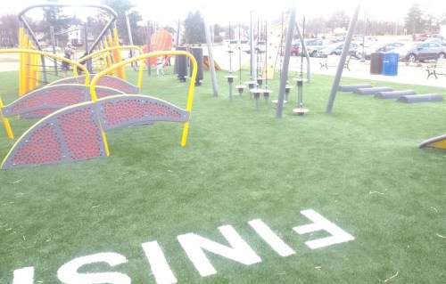 Colorful playground equipment on artificial grass, with a "FINISH" sign visible in the foreground.