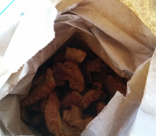 A brown paper bag filled with crispy, golden-brown pork rinds.
