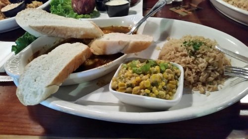 A plate with bread, rice, and a side of corn salad, served on a wooden table.