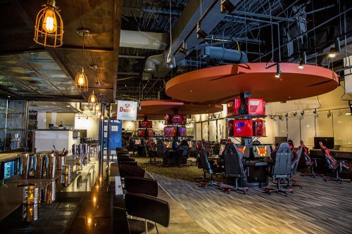 A modern gaming lounge with gaming stations, stylish seating, and ambient lighting.