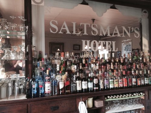 A bar display at Saltsman's Hotel featuring a variety of bottles and glasses on shelves.