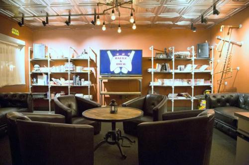 Cozy lounge with leather chairs, a round table, and shelves filled with books and games, featuring a TV displaying "Battle & Brew."