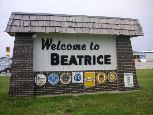 Welcome sign for Beatrice, featuring various local organization logos and a grassy area in front.