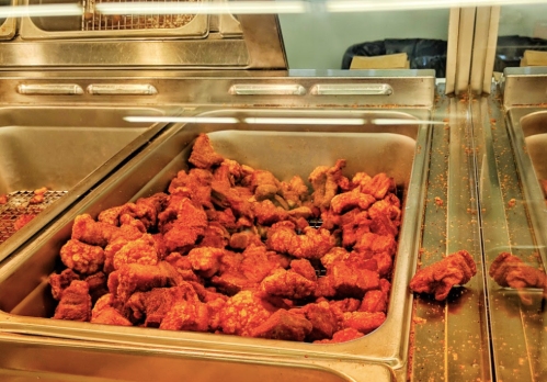 A metal tray filled with crispy, golden-brown fried chicken pieces.