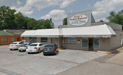 Exterior of Bino's Seafood Restaurant, featuring a sign, awning, and parked cars in a sunny setting.