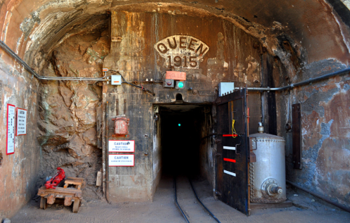 Entrance to the Queen Mine, marked with a sign from 1915, featuring wooden doors and mining equipment.
