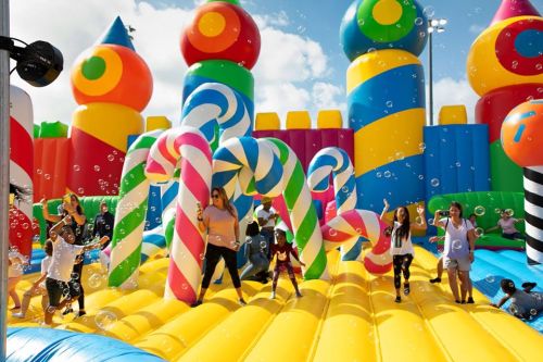 Colorful inflatable playground with children playing and bubbles floating in the air. Bright, festive atmosphere.