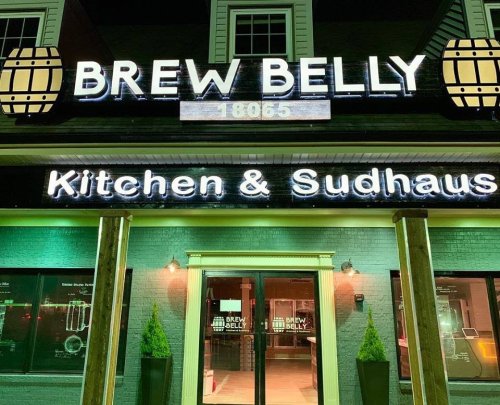 Exterior of Brew Belly Kitchen & Sudhaus, featuring illuminated signage and a welcoming entrance at night.