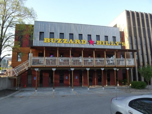 Exterior of Buzzard Billy's restaurant, featuring a wooden facade and large yellow signage, with outdoor seating on a balcony.