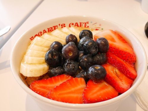 A bowl of oatmeal topped with sliced bananas, strawberries, and blueberries.