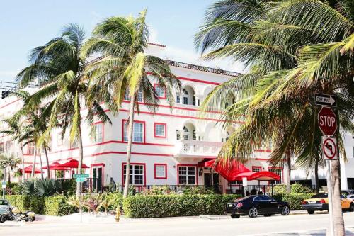 A colorful building with palm trees and outdoor seating, located on a sunny street with a stop sign nearby.