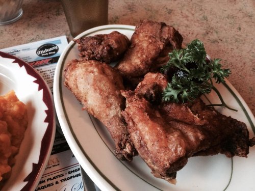 A plate of crispy fried chicken wings garnished with parsley, served on a white dish.