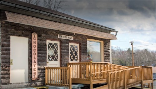 A rustic wooden building with a sign reading "Chocolates" and a ramp leading to the entrance.