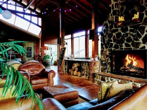 Cozy living room with a stone fireplace, leather furniture, and large windows letting in natural light.
