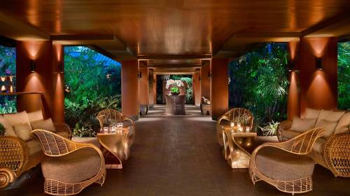 Luxurious lounge area with woven furniture, soft lighting, and lush greenery in a serene, tropical setting.