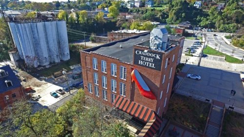 Aerial view of the Craddock Terry Hotel featuring a large red high heel on its exterior, surrounded by greenery and buildings.