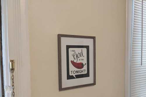 A framed sign on a wall reads, "I feel God in this tonight!" with a chili pepper graphic.