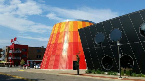 Colorful modern buildings with a cylindrical structure and a black building featuring circular windows under a blue sky.