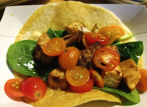 A tortilla filled with grilled chicken, fresh spinach, and cherry tomatoes.