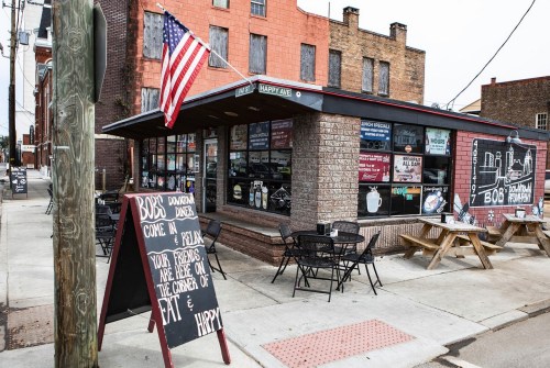 A corner diner with outdoor seating, an American flag, and a sign inviting friends to relax at Bob's Downtown Diner.