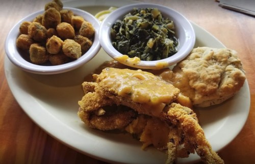 A plate of fried crab with gravy, biscuit, collard greens, and fried okra.