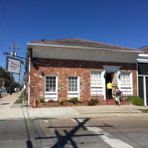 A brick building with white trim and a sign reading "Dough's Bakery," featuring a clear blue sky above.