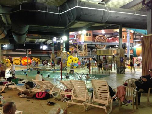 Indoor water park scene with children playing in the pool, water slides, and lounge chairs around the area.