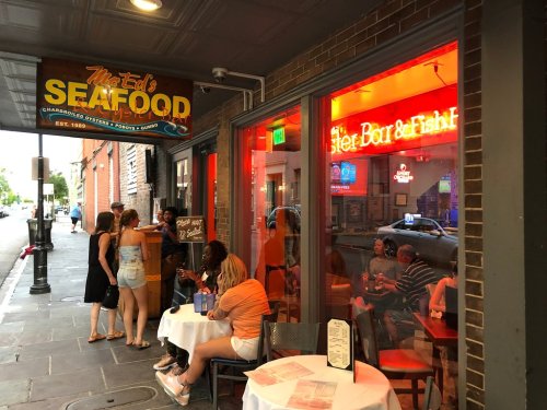 A seafood restaurant with a vibrant exterior, featuring outdoor seating and patrons enjoying their meals.