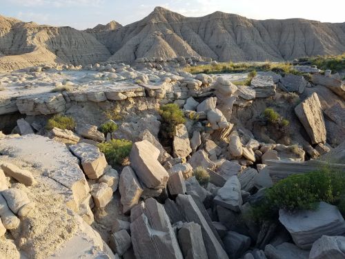 Rocky terrain with layered formations and sparse vegetation under a clear sky.