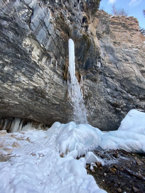 A frozen waterfall cascading down a rocky cliff, surrounded by ice and snow in a winter landscape.