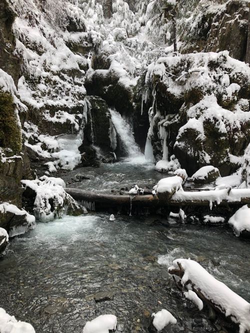 A serene winter scene featuring a waterfall surrounded by snow-covered rocks and icy formations.