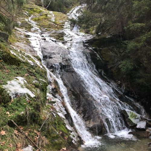 A serene waterfall cascading over rocky terrain, surrounded by lush greenery and moss.