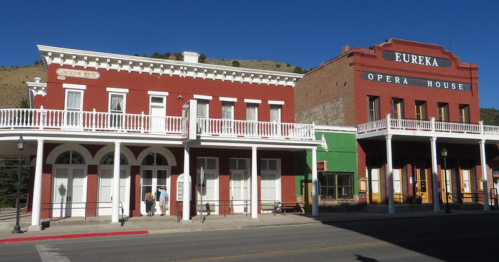 Historic buildings in Eureka, featuring the red Eureka Opera House and a white balcony structure under a clear blue sky.