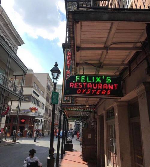 Neon sign for Felix's Restaurant and Oysters on a street with people walking in a lively urban setting.