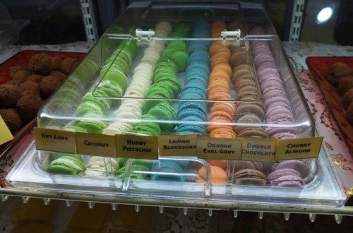 A display of colorful macarons in various flavors, arranged neatly in a clear container.