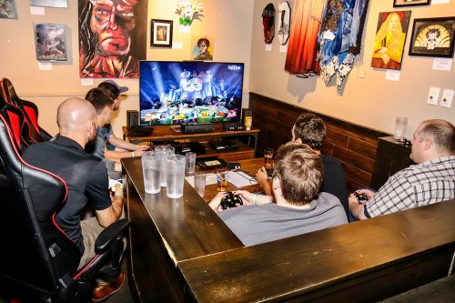 A group of people playing video games together in a cozy gaming lounge, focused on the screen.