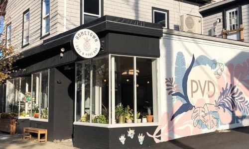 Exterior of Hometown Cafe & Poke Bar, featuring large windows and a colorful mural with "PVD" on the wall.