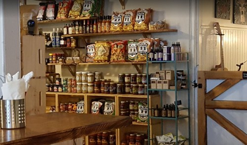 A cozy shop interior featuring shelves stocked with snacks, sauces, and various products.