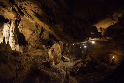 A dimly lit cave with rocky walls and a winding path, illuminated by scattered lights.