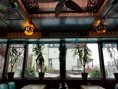 Interior of a restaurant with decorative ceiling, plants, and snowflake decorations in the windows.